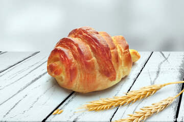 Freshly Baked Golden Croissants with Wheat Stalks on Rustic Wooden Table