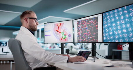 Man Analyzing Protein Structures On Multiple Computer Screens