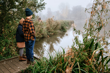 Boy and girl standing near tall grass on the wooden pier.