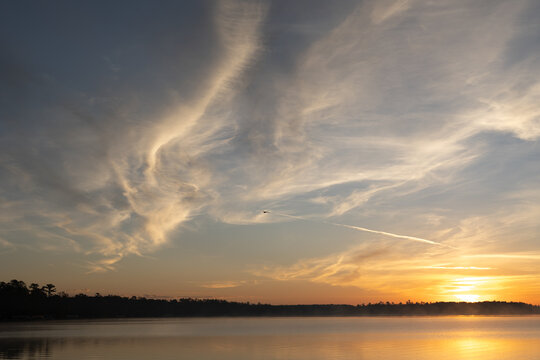 Golden sunrise over lake with dramatic swirling cloud patterns