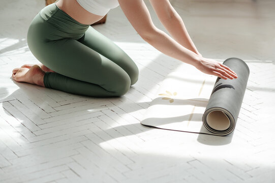 Fit woman rolling black fitness rug before working out