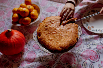 Child cutting homemade cake on patterned tablecloth