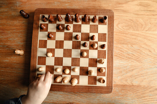 Chessboard with pieces and child&rsquo;s hand.