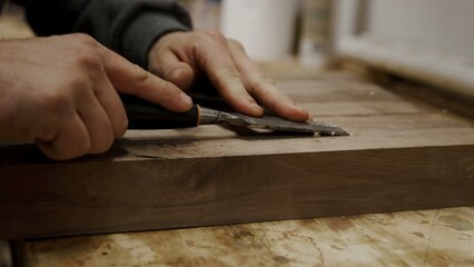 Skilled craftsman's hands carefully chisel dark wood for a fine finish