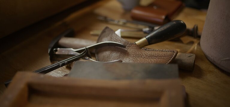 Fine leather tools arranged on a craftsman's wooden table surface