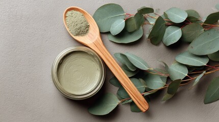 open jar of green clay mask surrounded by eucalyptus leaves and wooden spoon, matte texture, natural spa composition