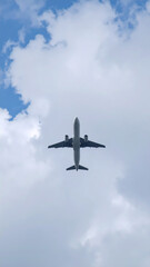 Fototapeta premium Airplane soaring through a cloudy sky on a bright day overhead perspective