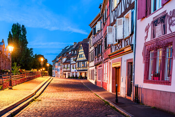 Colmar, Alsace, France: Colorful half timbered houses on the quays wharf at twilight