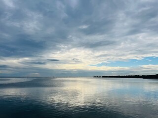 Calm Waters and Cloudy Skies: A serene coastal panorama captures the essence of tranquility, showcasing a vast expanse of calm water under a dynamic sky filled with fluffy clouds.