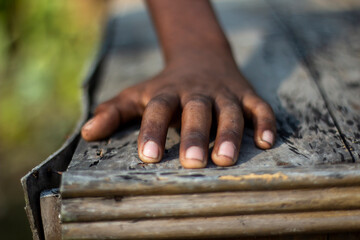 Childs hand rests on a weathered wooden surface, evoking a sense of touch and texture