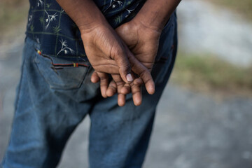 Close up of a mans hands clasped behind his back wearing blue jeans