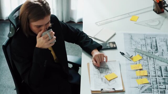 Top view of architect engineer drink coffee and draw blueprint at meeting table with equipment and safety helmet scatter around. Aerial view of project manager looking at project plan. Alimentation.