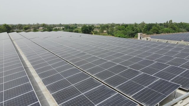 A high-resolution aerial view of a solar power plant with rows of photovoltaic panels and rooftop solar installations capturing sunlight for clean electricity generation, symbolizing green energy and 