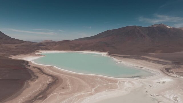 Aerial shot of the stunning Laguna Verde in the Bolivian Altiplano with vibrant turquoise waters, surrounding volcanoes and clear skies on a sunny day at high altitude in the Andes mountains