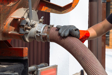 Septic service technician connects hose for tank pumping in residential area. Septic tank service. Sewage Tank truck.
