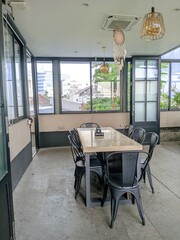 Cozy industrial-style cafe interior with wooden tables, metal chairs, and large windows with natural light. 