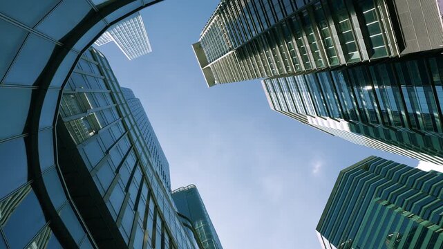 Low angle view of city skyline buildings, blue sky and glass mirrored facades.	

