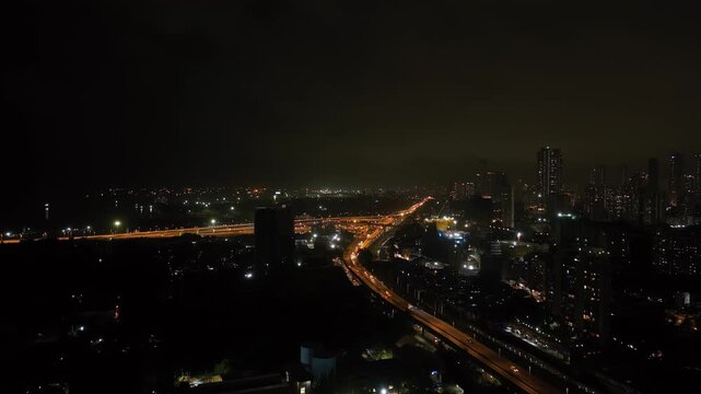 4K night view of a busy flyover bridge, highway, and monorail in Mumbai, Monorail passing side by side Skyscraper buildings in Mumbai at night, developing India concept