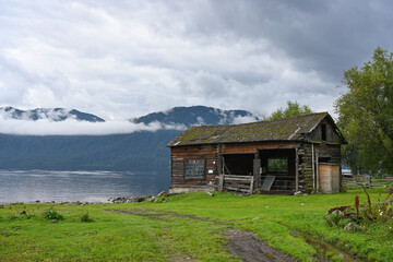Abandoned wooden barn on the shore of a picturesque mountain lake