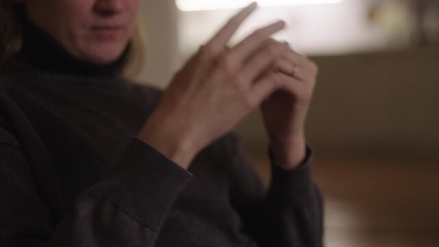 Close-up of woman having chronic pain in wrist joint due to cerebral palsy, gently holding forearm while coping with daily challenges of disability and neuropathic discomfort. Shooting in slow motion.