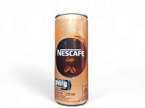 ​A vertical close-up of a golden-brown Nescafe Latte ready-to-drink coffee can, featuring a brown label and condensation, isolated against a clean white background, highlighting the product packaging.