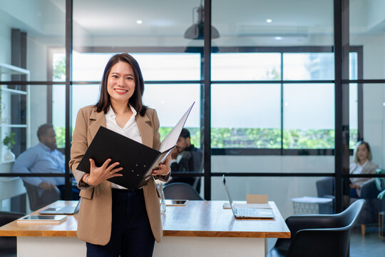 asian businesswoman in formal suit standing at coworking space in green office, group of multiracial team colleague diverse employee coworker meeting at environment sustainable workplace