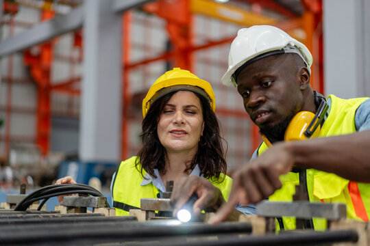 female engineer supervisor advice technician foreman to inspect and check spare part equipment of production machine, team of diverse workers working together at industrial manufacturing factory