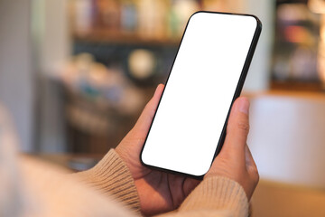 Mockup image of a woman holding and using mobile phone with blank desktop screen in cafe