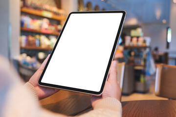 Mockup image of a woman holding digital tablet with blank white desktop screen in cafe