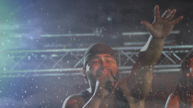 Falling snow revealing lead singer gripping mic and raising arm while concluding concert verse