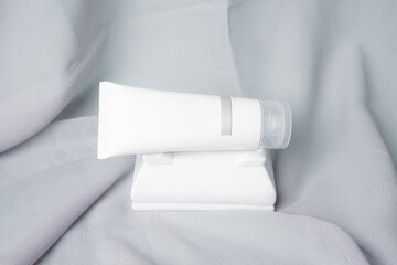 A facial soap bar is placed on top of a white flower vase resting on gray fabric