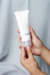 A facial soap bar is held gently by hand over a soft gray fabric