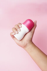 A Rexona bottle is held firmly by hand against a pink background
