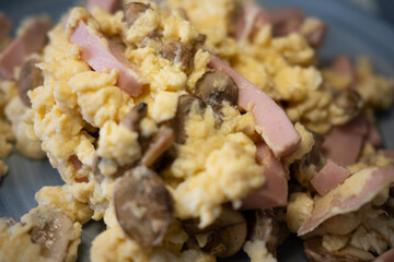 Appetizing close-up of fluffy scrambled eggs with savory ham and fresh mushrooms. A perfect concept for a hearty breakfast or brunch, showcasing a delicious and high-protein meal.