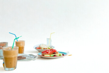 Refreshing iced coffee and colorful dessert spread on a white table