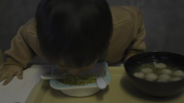 Toddler Is Eating Noodles By Himself, A cinematic ad film of a toddler slurping noodles solo, sauce on chubby cheeks under warm light, perfect for a baby food commercial or a delightful documentary.