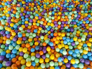 Colorful  plastic balls in a large pool, known as a ball pit. Their bright and vibrant colors naturally attract children to play and dive in