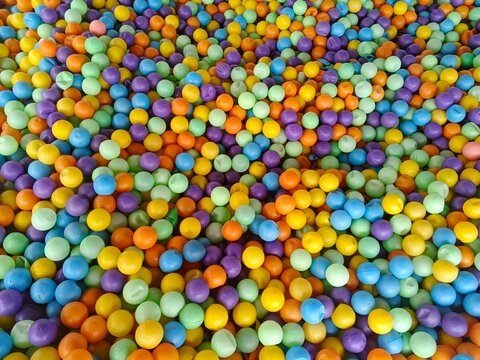 Colorful  plastic balls in a large pool, known as a ball pit. Their bright and vibrant colors naturally attract children to play and dive in