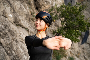 Young female athlete climber stretching hands before outdoor rock climbing, physical preparation and wellness in mountain environment