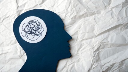 Tangled thoughts concept showing mental health struggles and anxiety, blue human head silhouette with chaotic mind on textured paper background