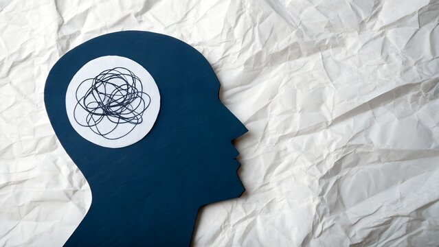 Tangled thoughts concept showing mental health struggles and anxiety, blue human head silhouette with chaotic mind on textured paper background