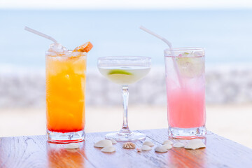 Refreshing cocktails on tropical beach table, vibrant colors, relaxation, summer, ocean backdrop, shells, wooden surface, vacation mood.