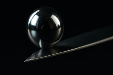 Balance in Motion – Metallic Sphere Resting on Edge of Blade