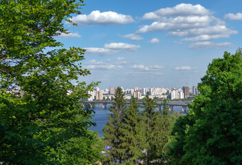 City skyline view from a green park by the river on a sunny day with fluffy clouds in the sky