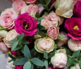 Vibrant bouquet of pink and cream flowers arranged beautifully with green leaves in a soft, natural light setting .