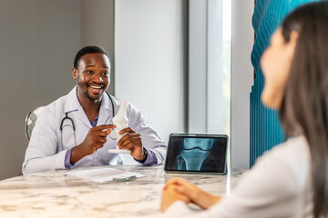 Cheerful doctor and young woman discuss her X-ray from a knee boneresults on a tablet computer. A man analyzes an MRI image to make a diagnosis for a patient, Female consulting trauma surgeon