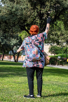 Mujer de 60 a&ntilde;os alegre y sonriente en el parque  saludando con los brazos