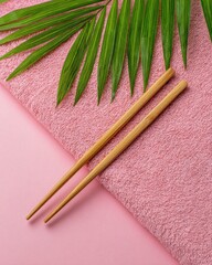 Gold Chopsticks on Pink Towel with Palm Leaf.