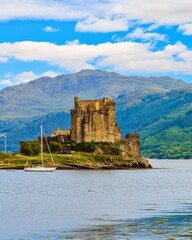 Fototapeta premium Historic castle on island in scottish loch with mountains