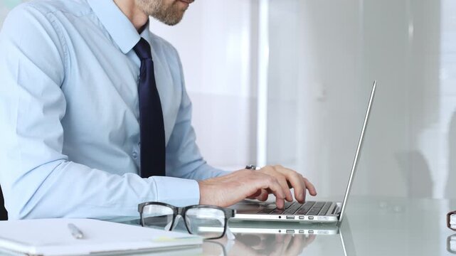 Businessman working on laptop in office, typing keyboard, focusing on professional corporate tasks. Business people concept